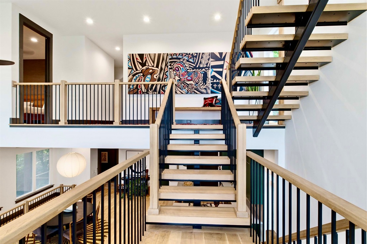 Striking black spiral staircase anchors this double-height space w/ bold architectural drama.
