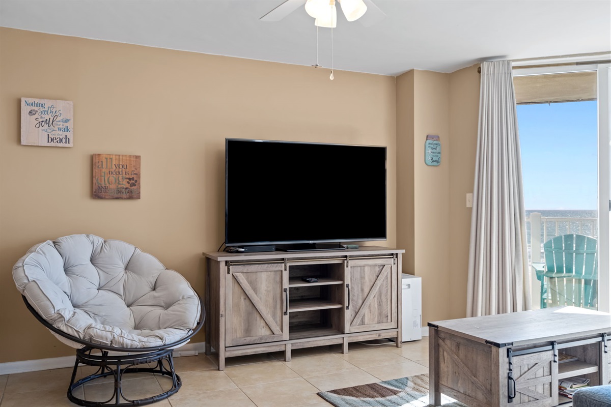 Cozy entertainment nook with oversized TV, inviting lounge chair, and easy access to the balcony for ocean breezes