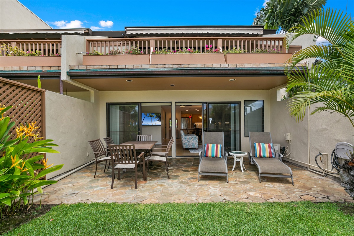 View into Maui Kamaole I-103 from the lawn. Two chaise lounges, patio table with seating for six