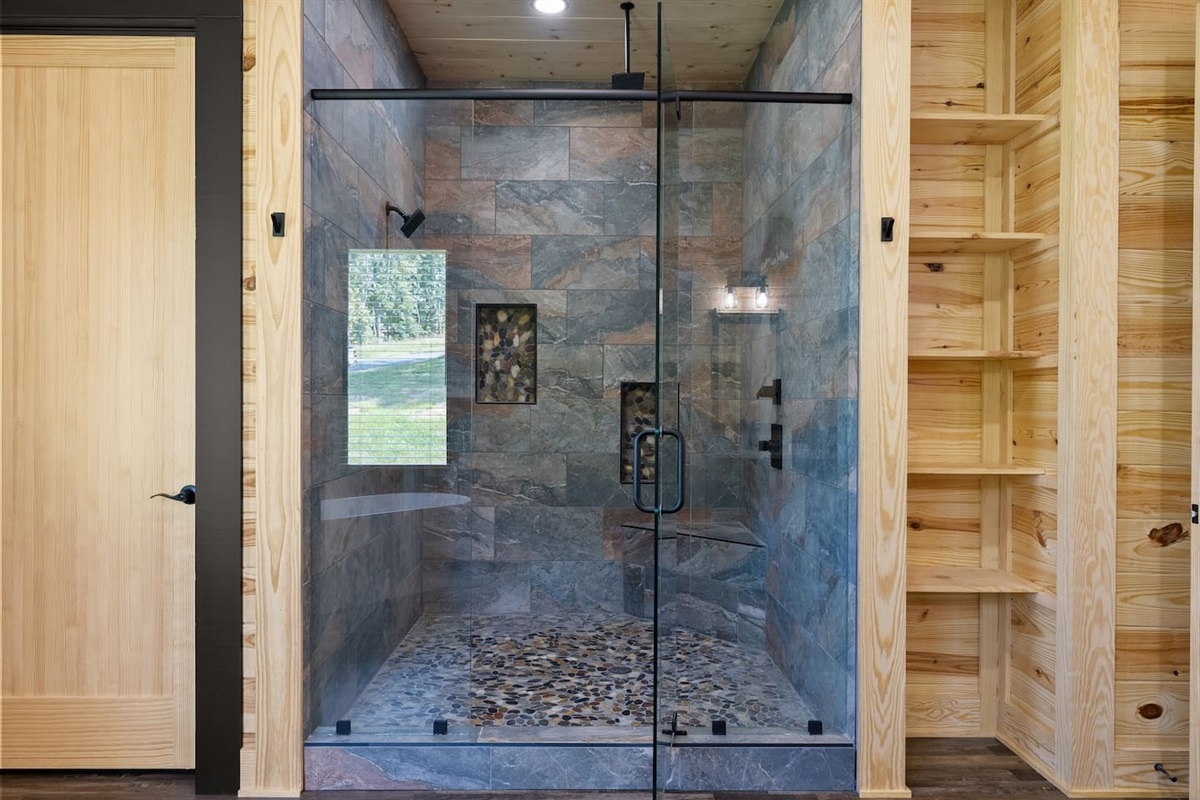 Refresh in style in this oversized glass walk-in shower with natural stone tile and rainfall showerhead.

