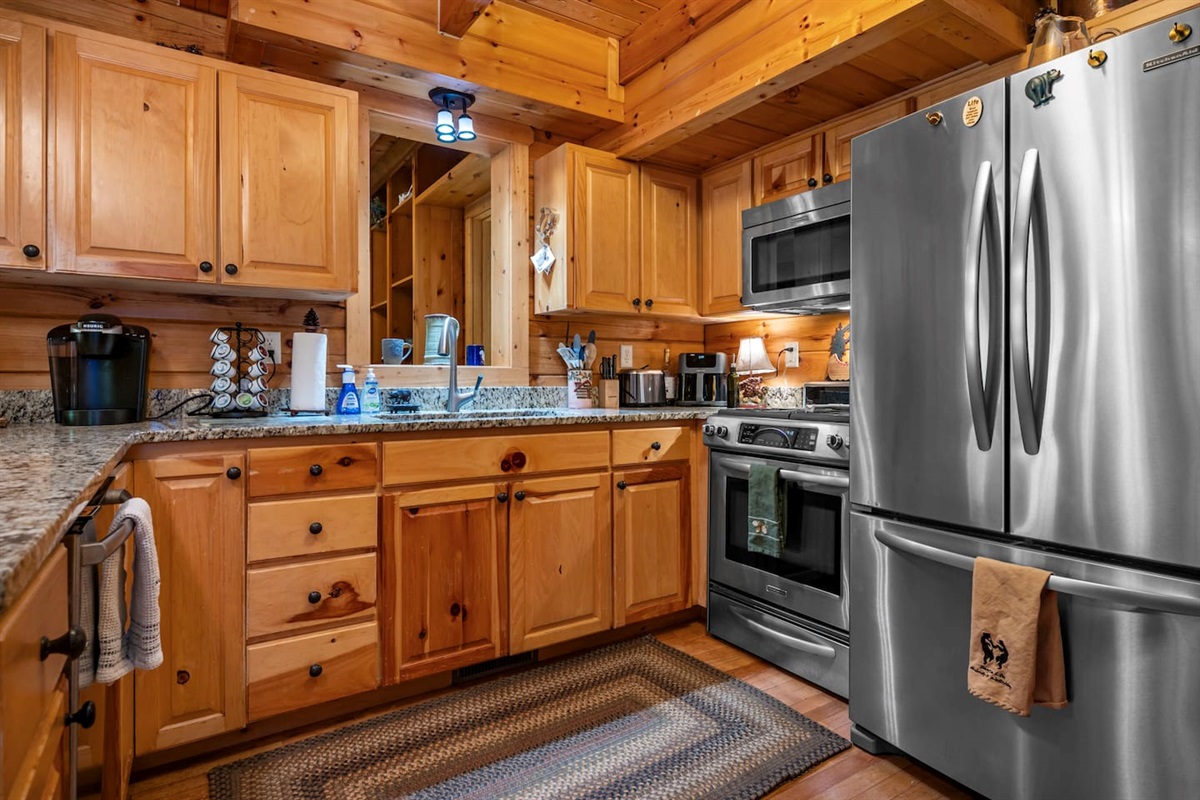 Fully stocked kitchen with warm wood cabinetry, granite countertops, and stainless steel appliances, creating a welcoming space to cook and gather. Includes a coffee station, ample prep space, and all the essentials needed for a comfortable stay.