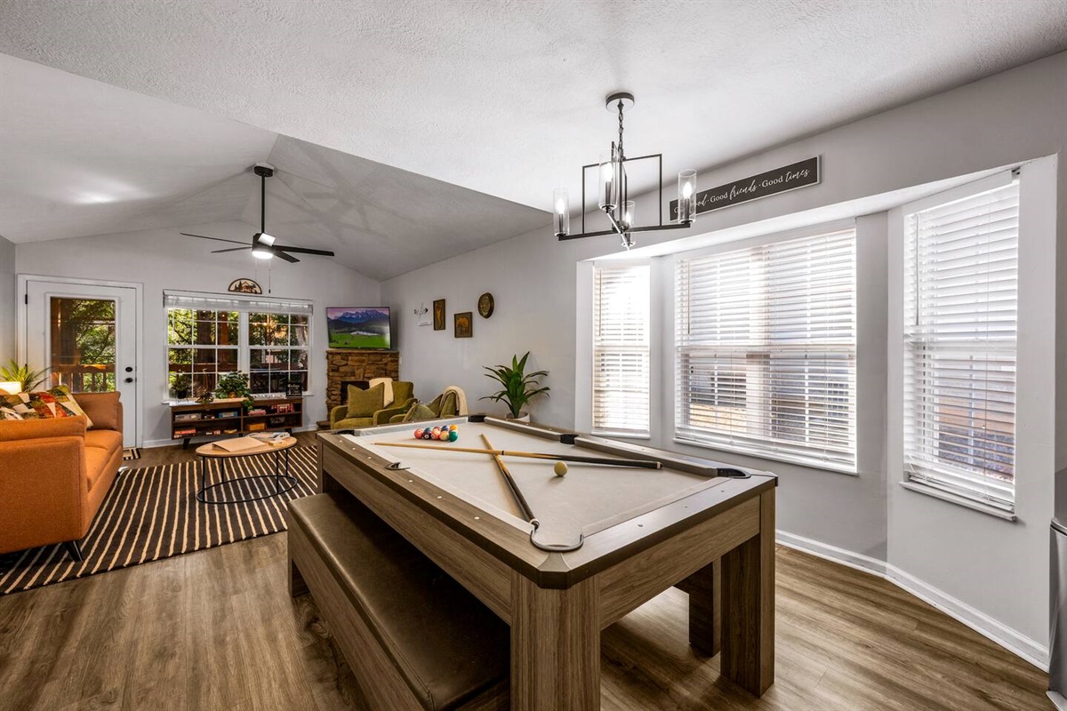 Bright game room with a pool table, cozy seating, and large windows for natural light.
