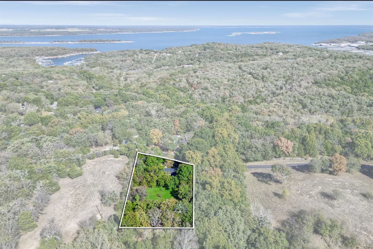 Aerial view outlining the property boundaries, highlighting the expansive lot, wooded surroundings, proximity to lake, and private setting.