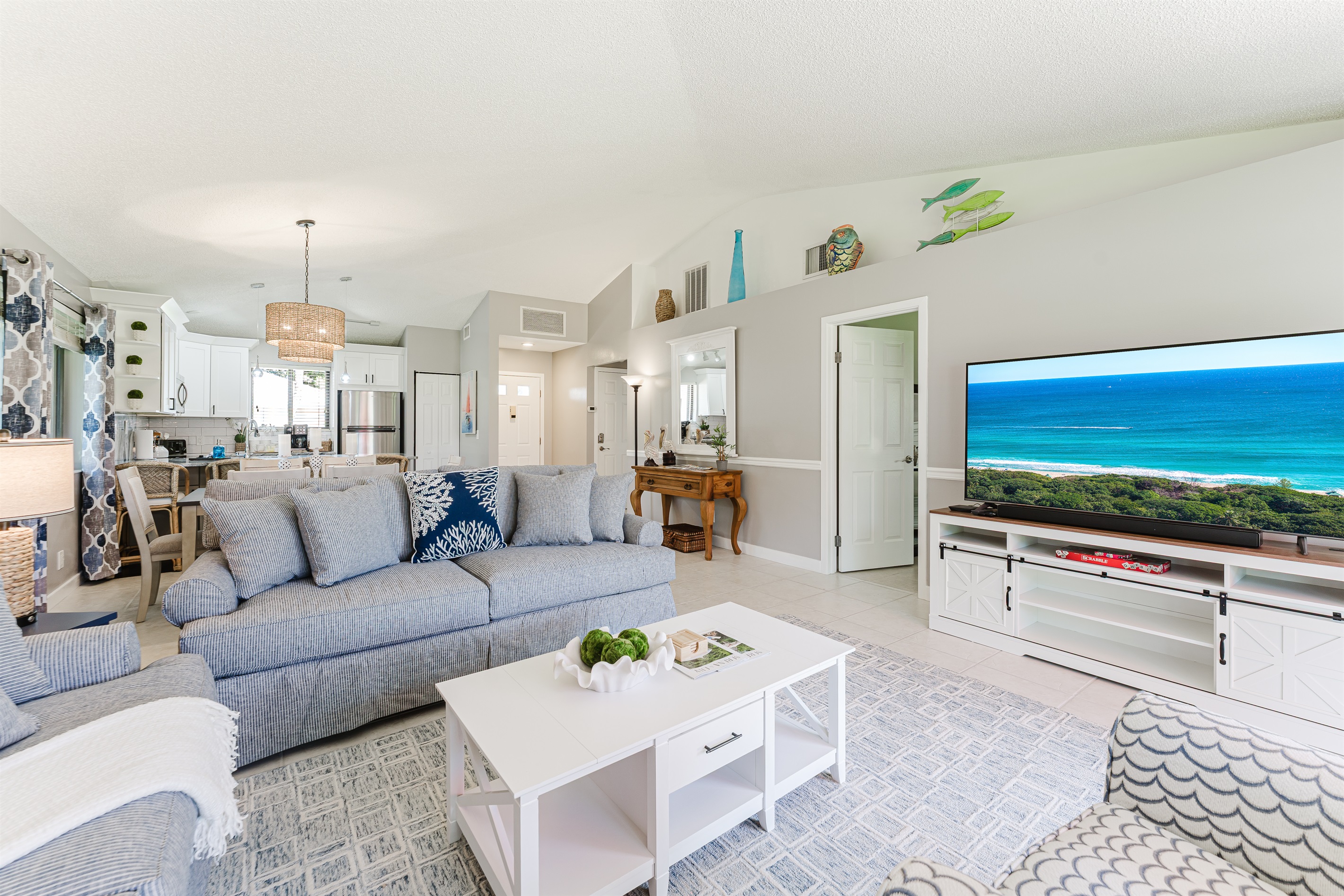 Bright and spacious coastal-inspired living room with oversized seating, Smart TV, cable, and direct access to the patio and outdoor dining area.
