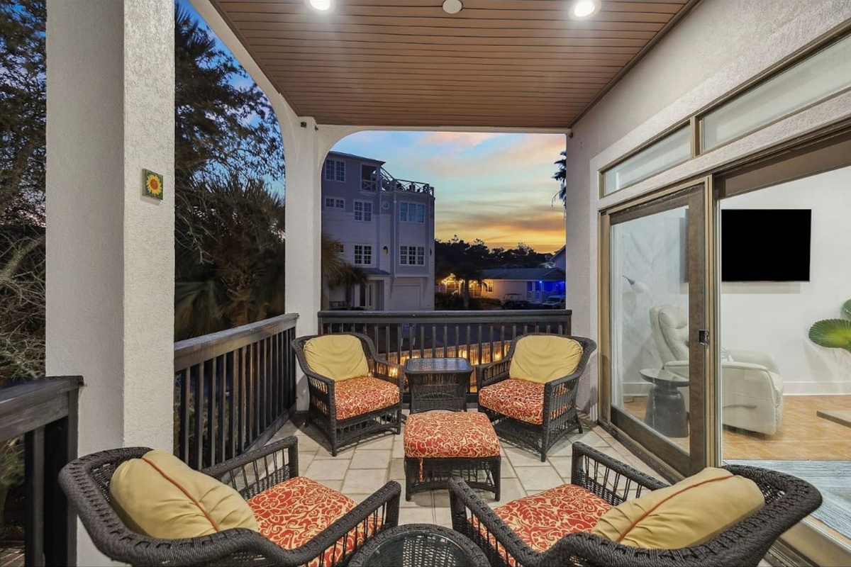 Expansive covered main-level balcony equipped with cozy outdoor furnishings, providing a perfect open-air gathering spot to enjoy the coastal breeze