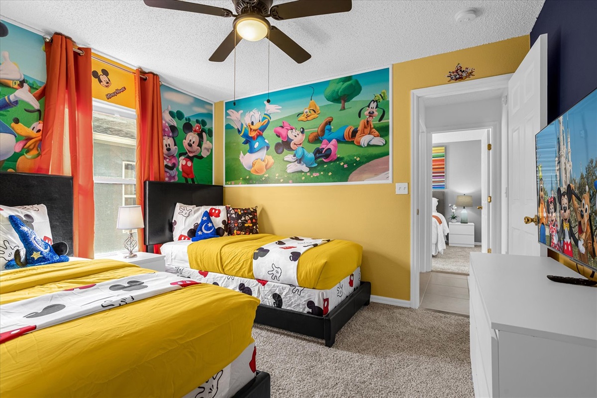 Children's bedroom featuring 2 twin beds with colorful Mickey Mouse theme.