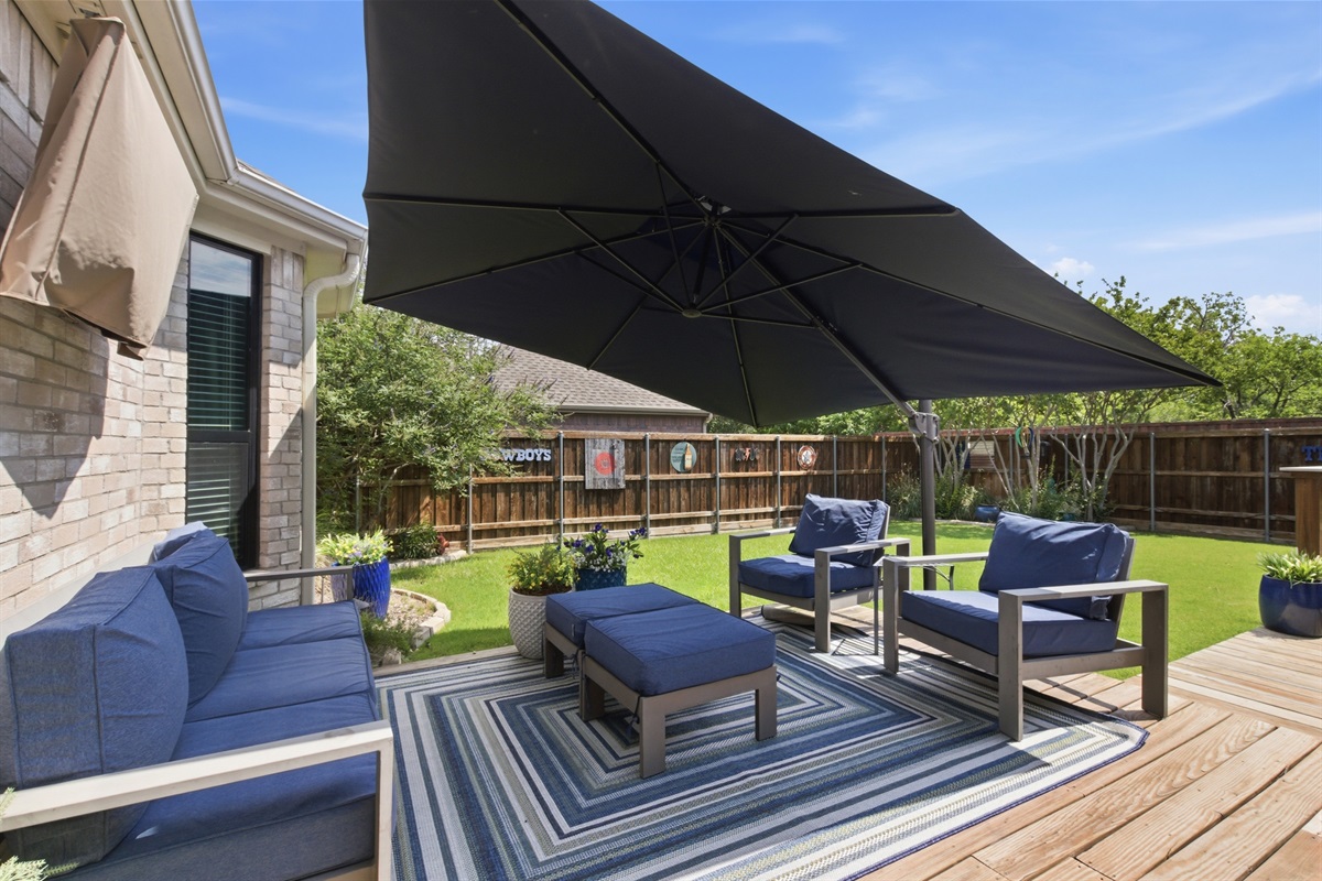 Wooden Deck with comfortable Outdoor Furniture, plush navy cushions, and a large shade umbrella for hot Texas afternoons.

