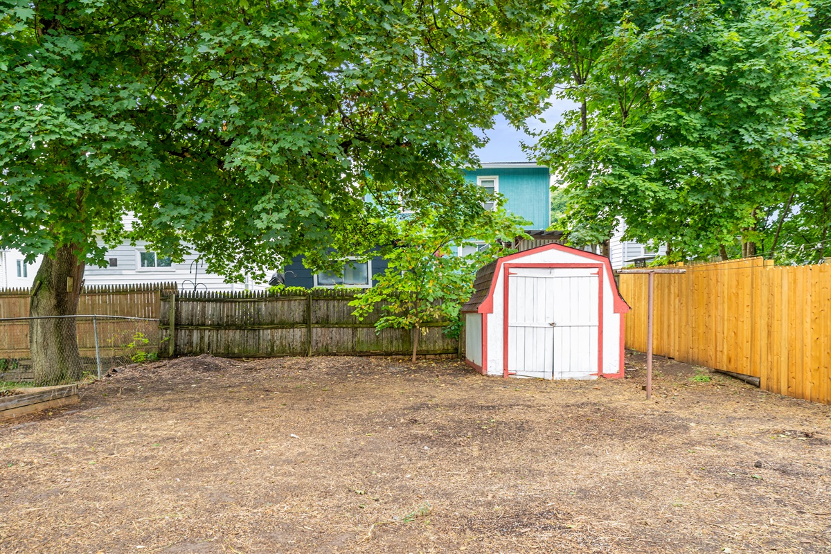 Fully fenced backyard with shade trees