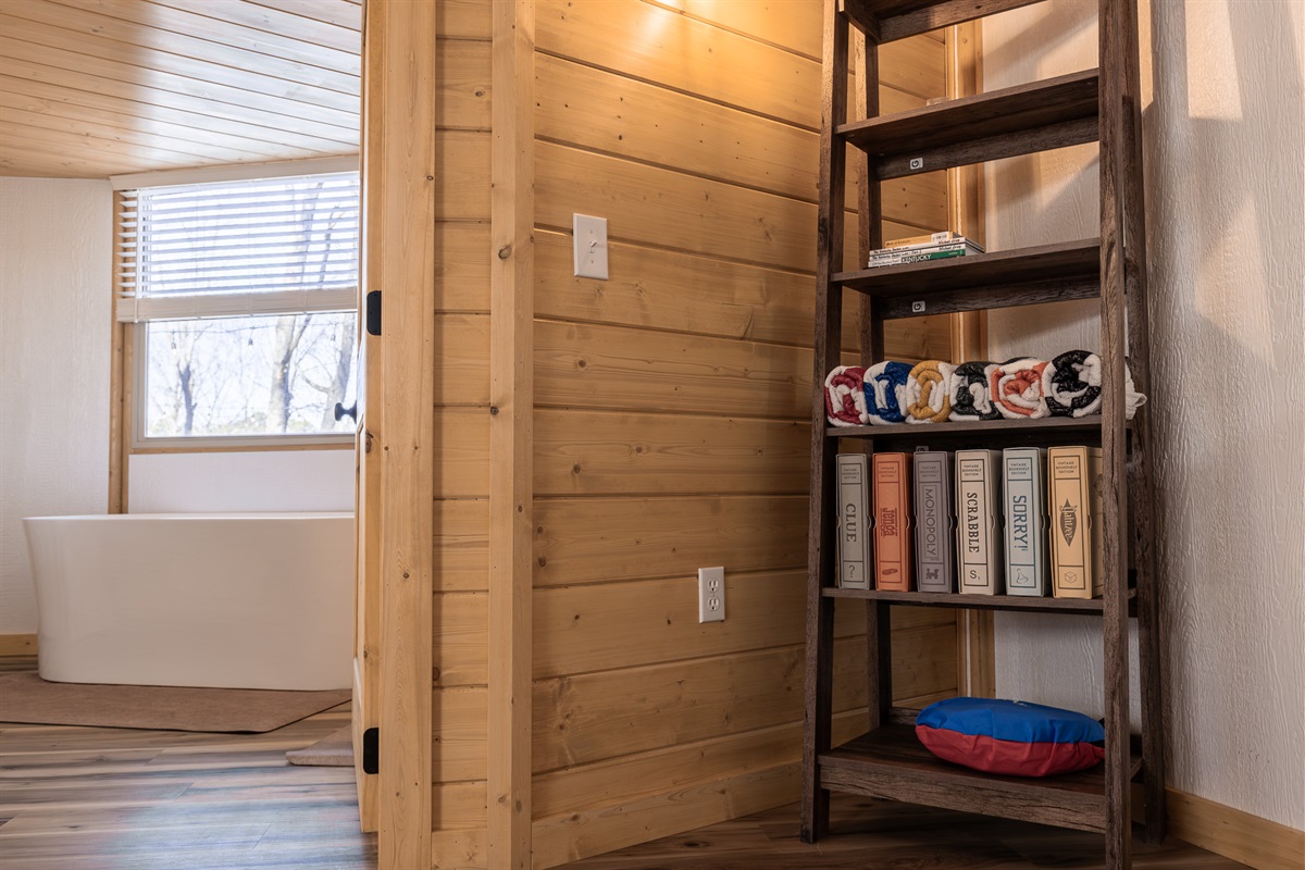Games, books, and towels just outside the spa-style soaking tub.