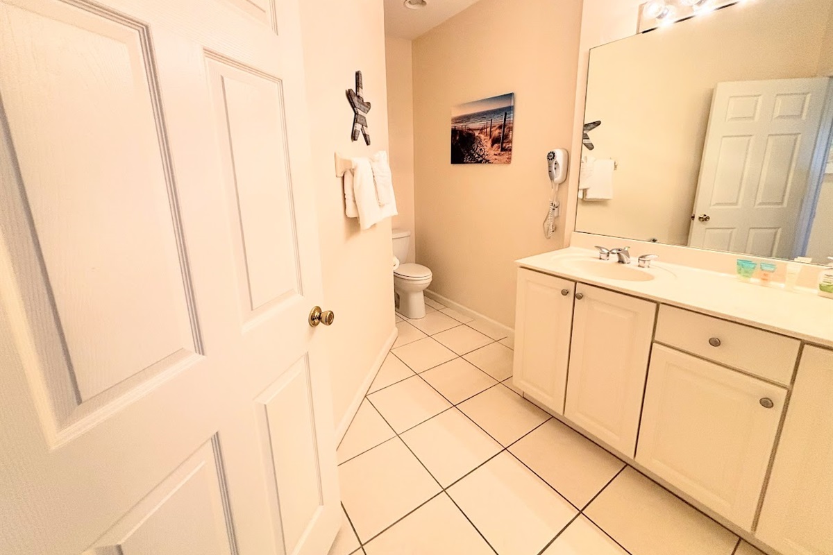 Clean and spacious bathroom featuring a large vanity, tile flooring, and neutral finishes.