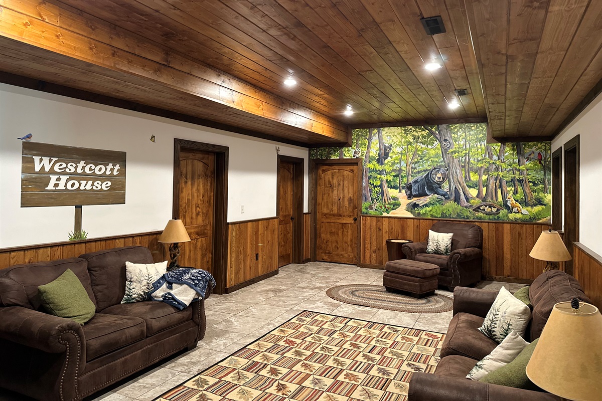 A cozy sitting room featuring a painted mural of a bear in a peaceful forest.