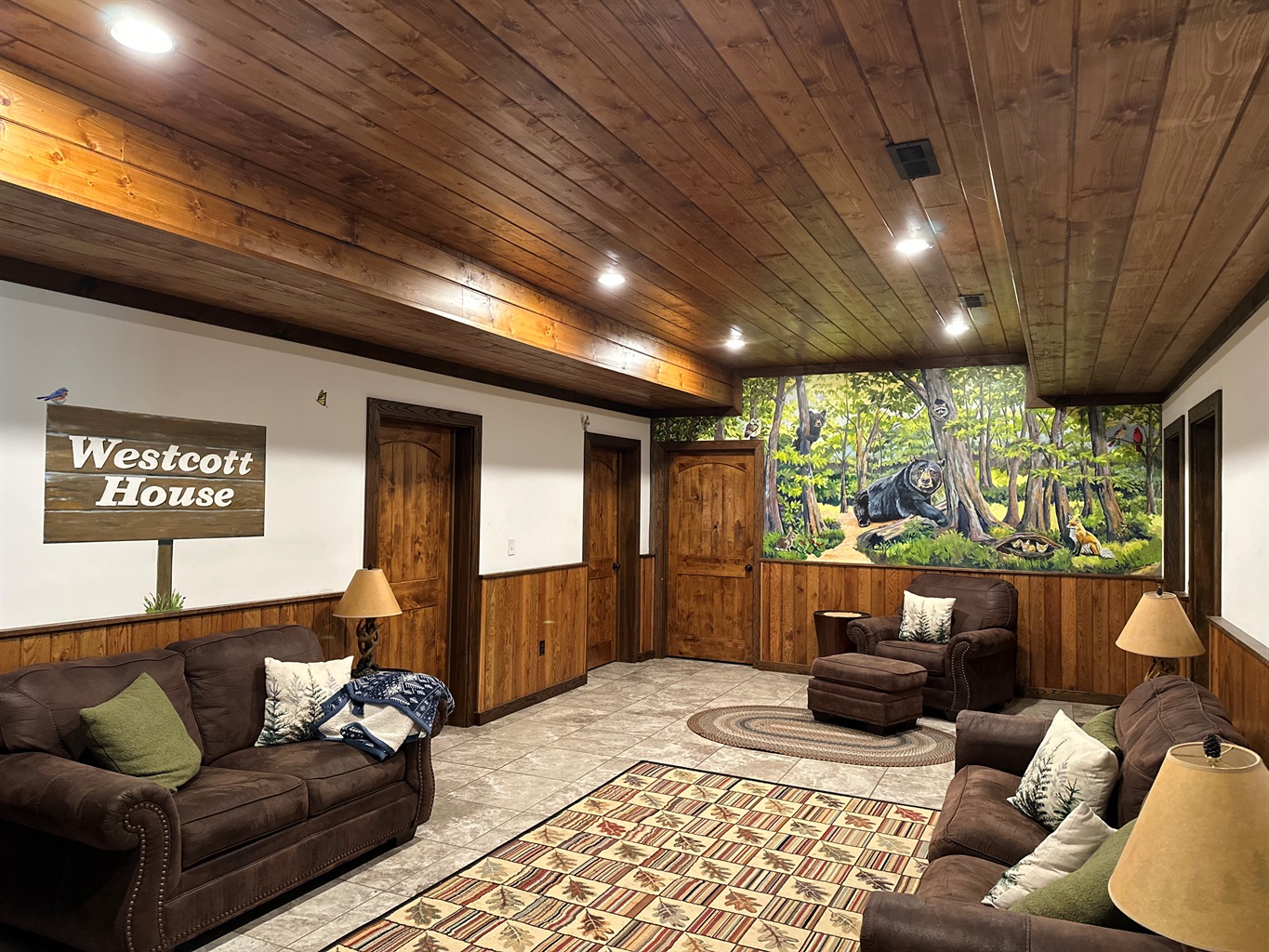 A cozy sitting room featuring a painted mural of a bear in a peaceful forest.
