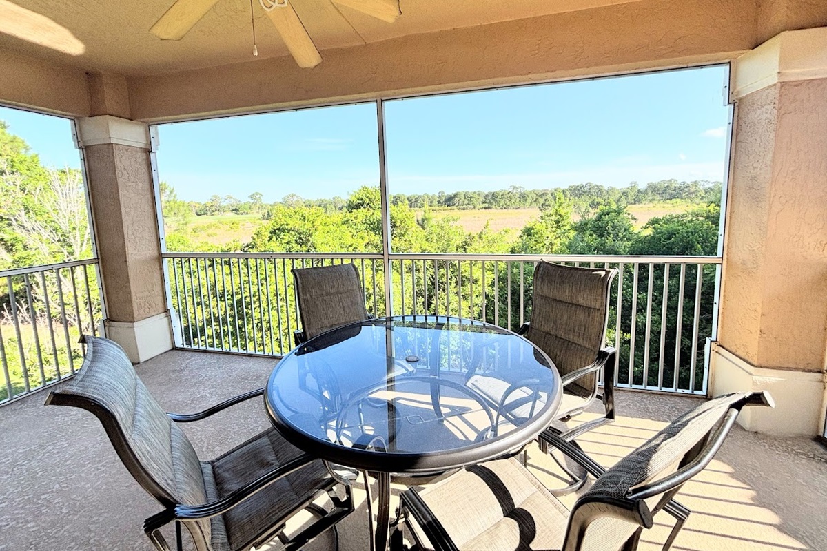 Private screened balcony with outdoor seating and peaceful views of the surrounding greenery.