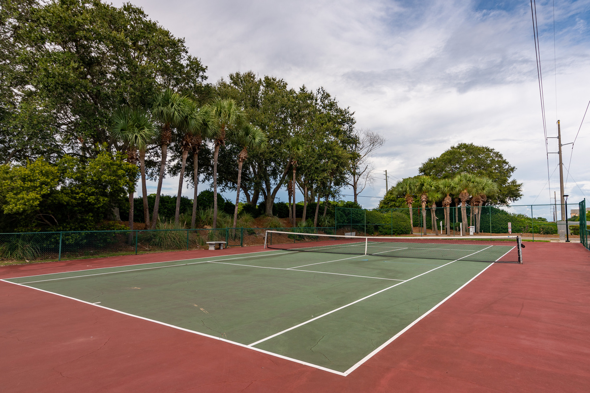 Community tennis court surrounded by lush greenery