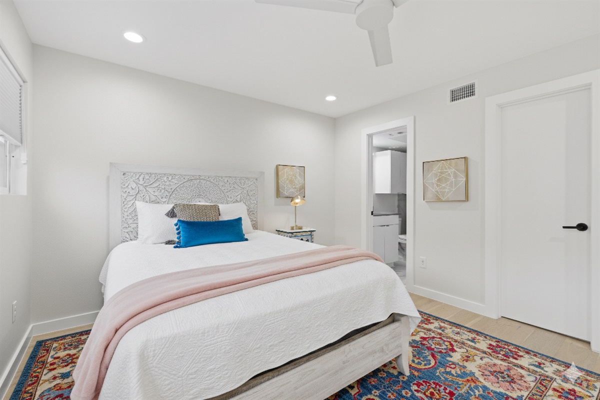 bedroom 1 with ensuite bathroom and queen bed, dresser, black out curtain