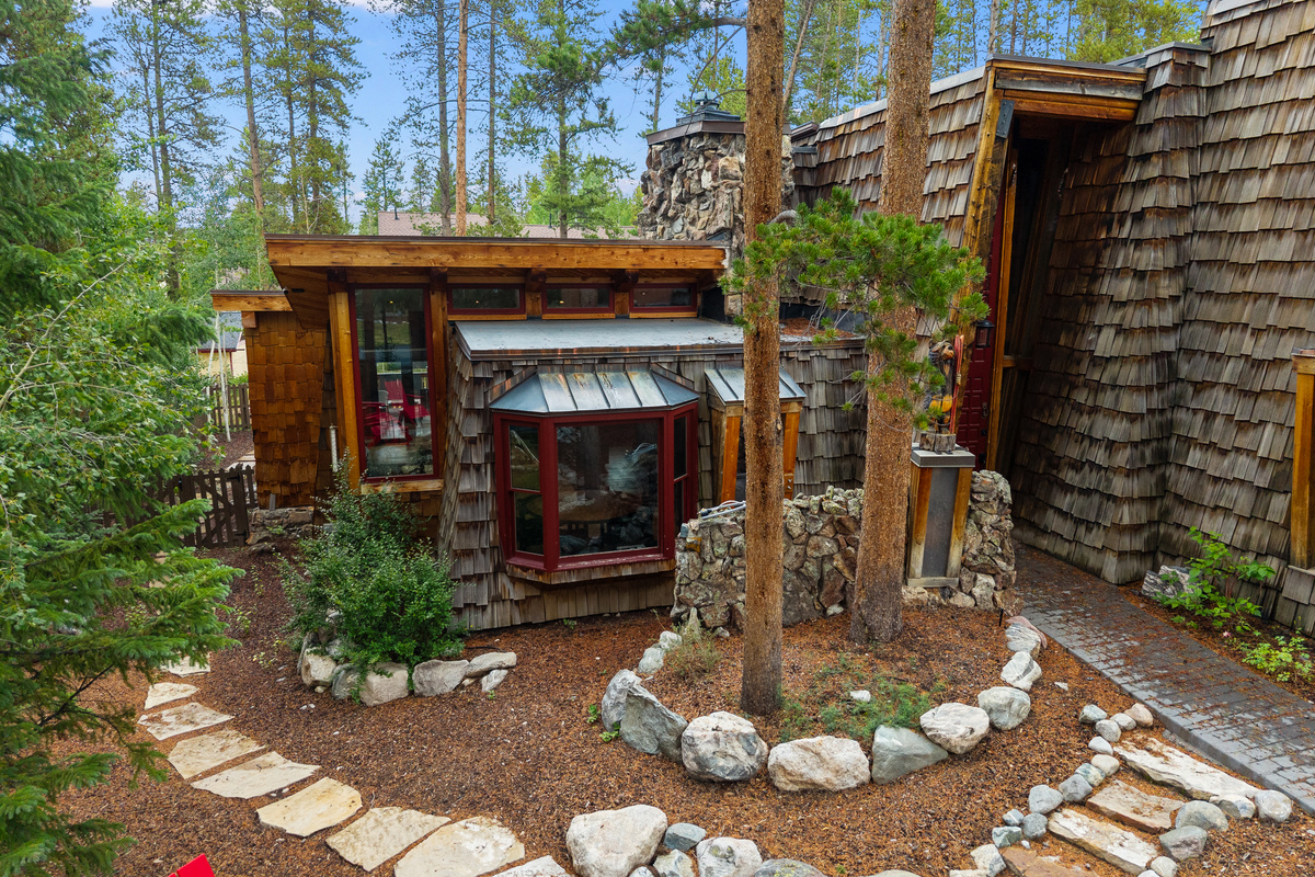 Front exterior in summer of Arrow Darrow, surrounded by towering lodgepole pines and rustic landscape