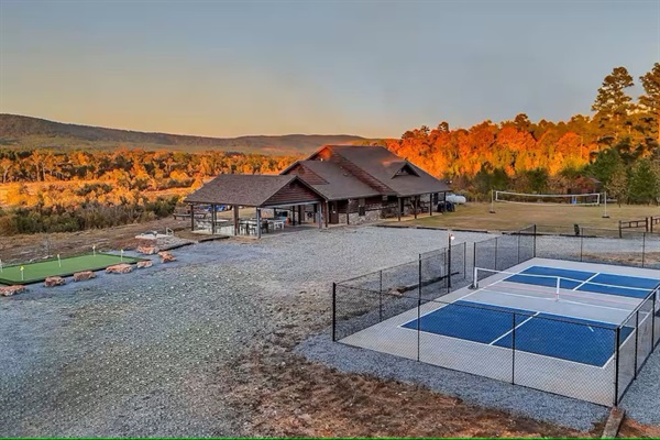 Aerial view showcasing the pickleball court, putting green, volleyball net and surrounding acreage.