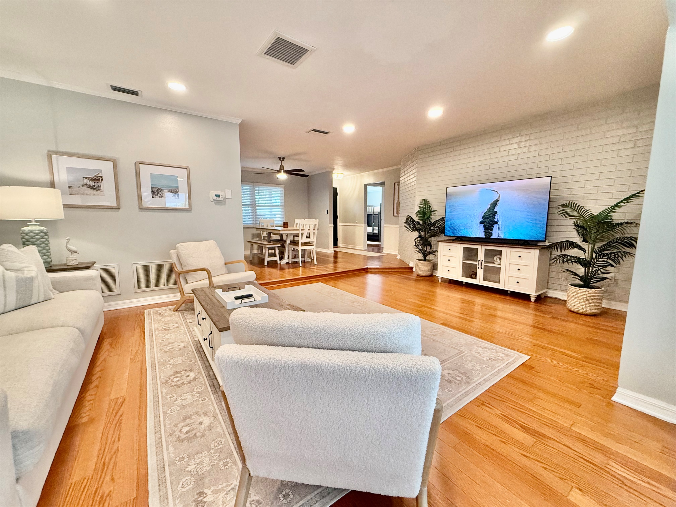 Stretch out and unwind in this spacious living area featuring warm wood floors, serene tones, and comfy furniture perfect for family time or movie night.