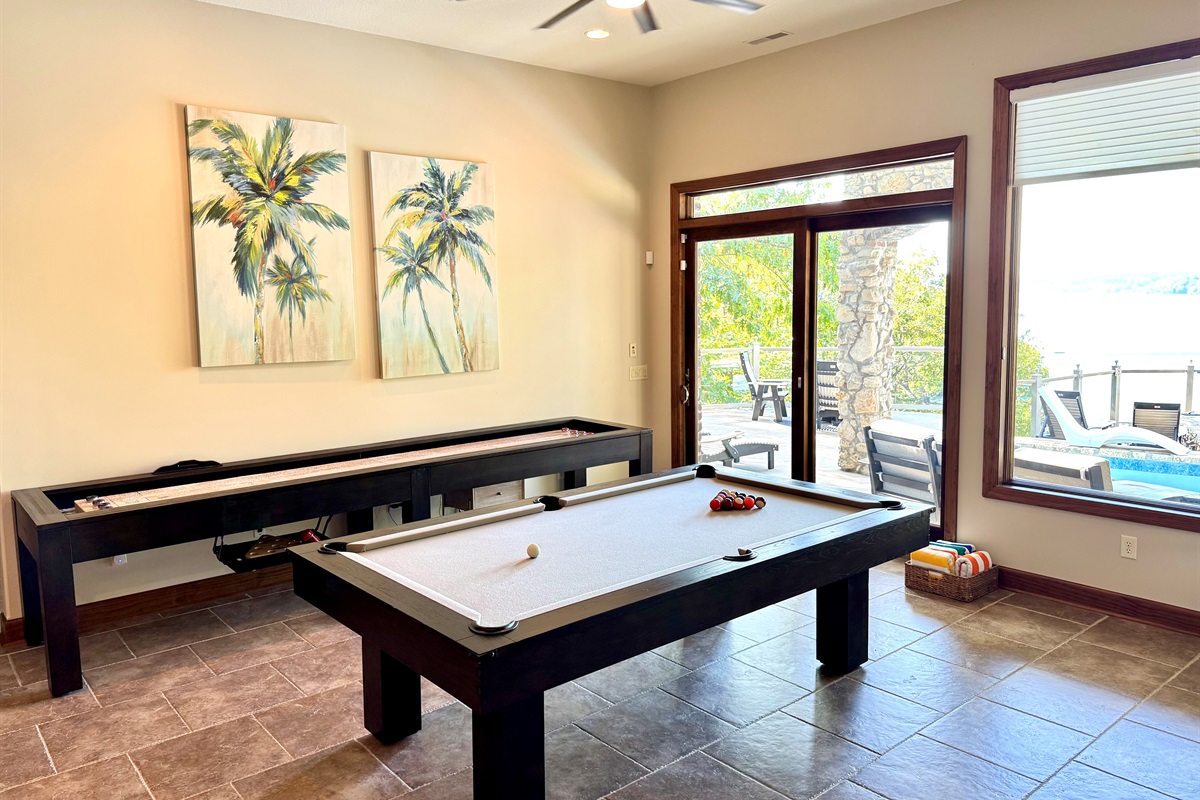 Lower level bar area has pool table and shuffleboard, stone gas fireplace, large 85” TV, bar with sink, dishwasher, microwave, and deep freezer.
