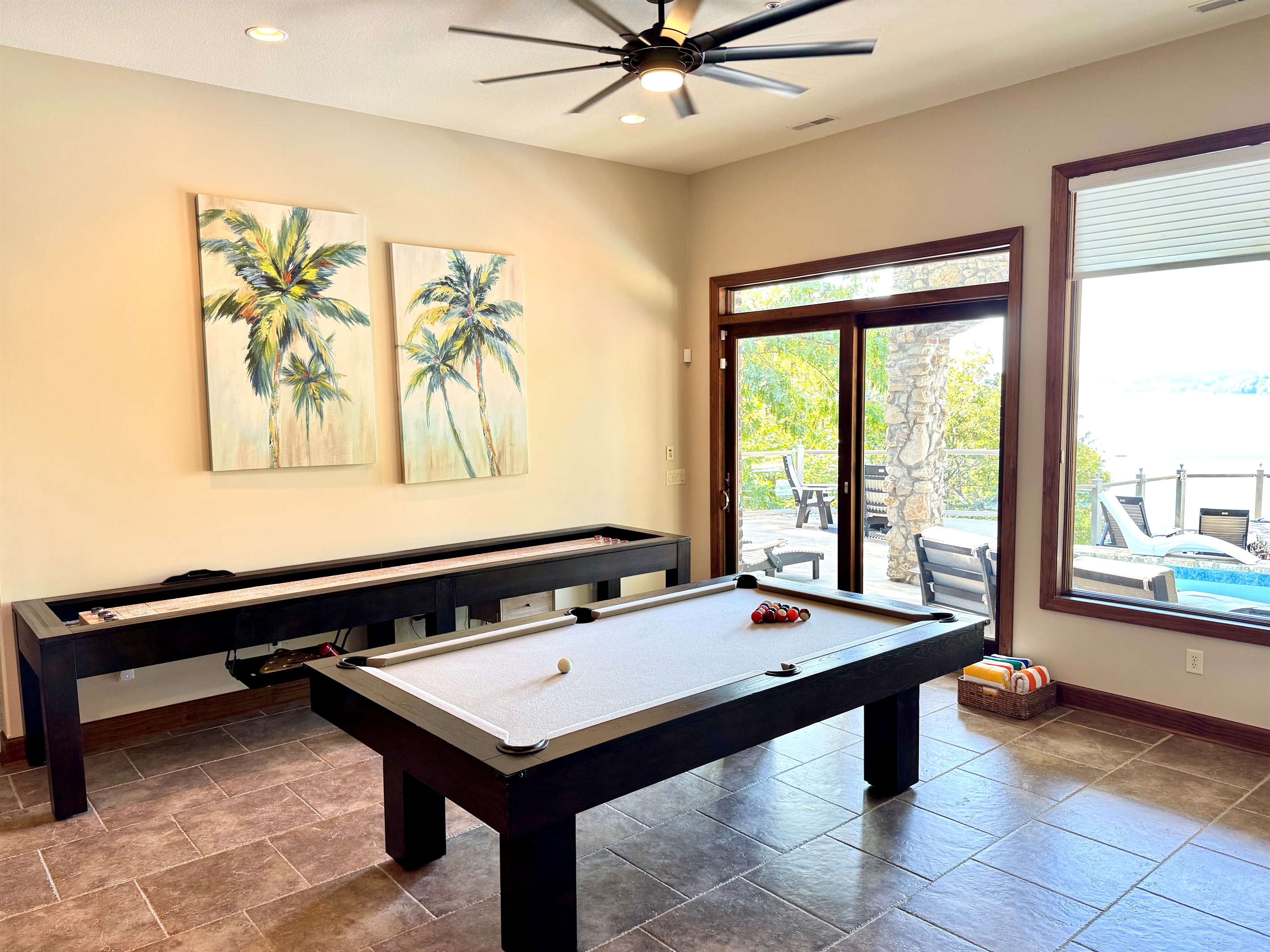 Lower level bar area has pool table and shuffleboard, stone gas fireplace, large 85” TV, bar with sink, dishwasher, microwave, and deep freezer.