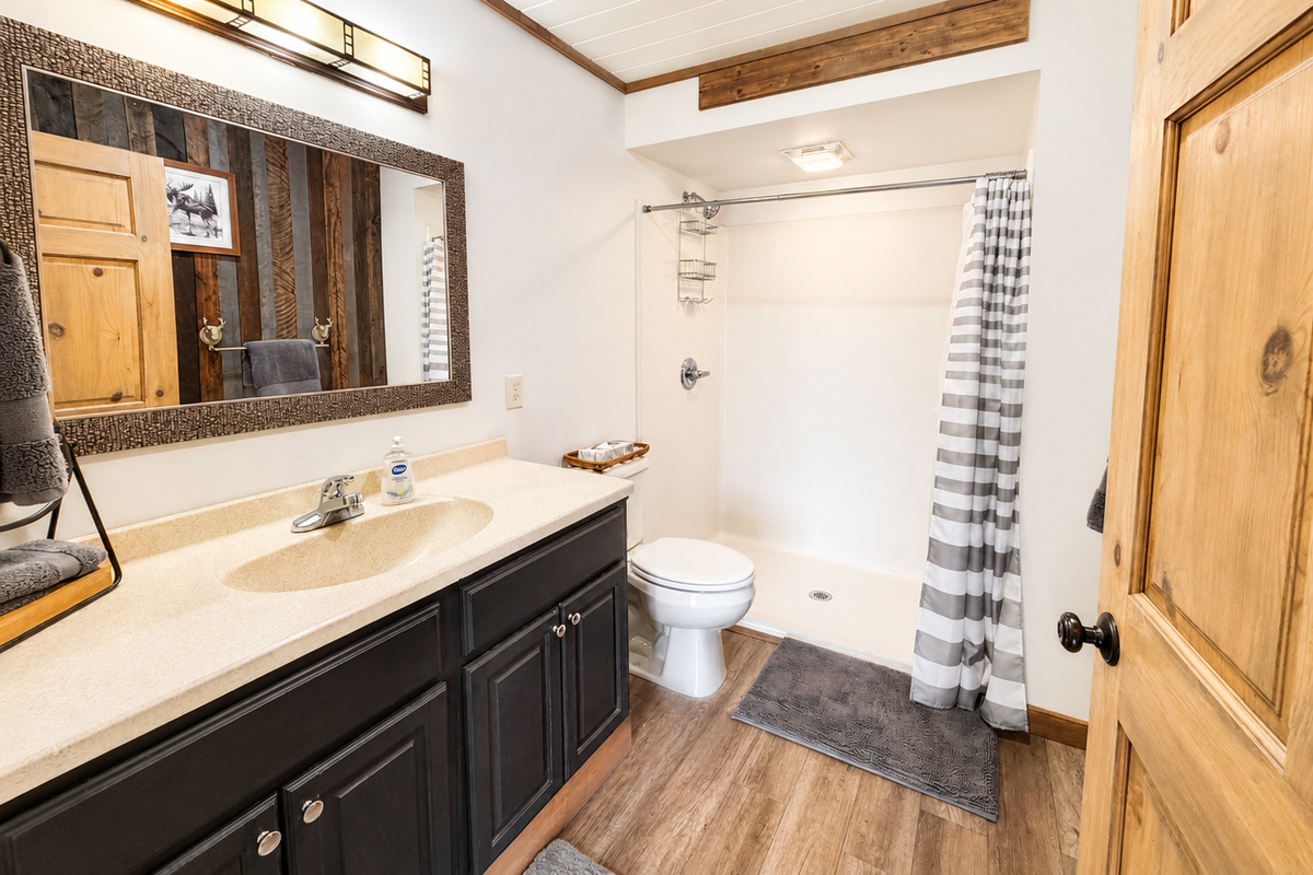 Full bathroom with a spacious vanity, shower and tub combination, and plenty of room to get ready, adding convenience for families and larger groups sharing the lodge. Conveniently located right off the kitchen and living room.