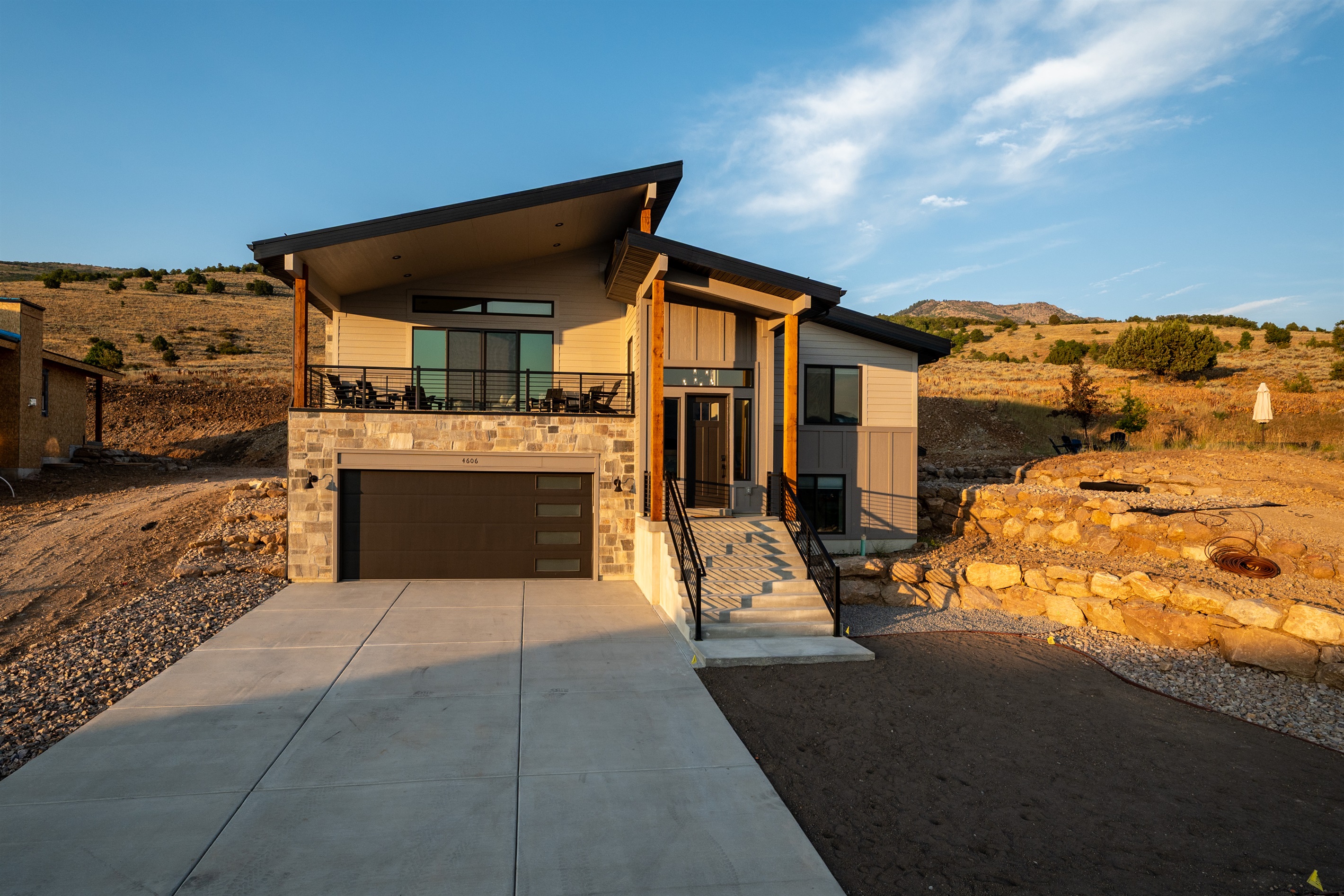 Front view of the home highlighting the deck, welcoming entryway, and spacious two-car garage with driveway.