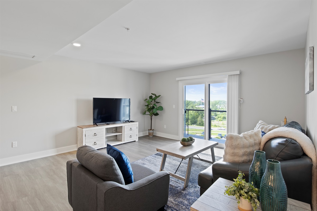 Enjoy spacious living with natural light flooding into this cozy living room, featuring stylish décor, a plush sofa, and a perfect spot to relax and unwind.