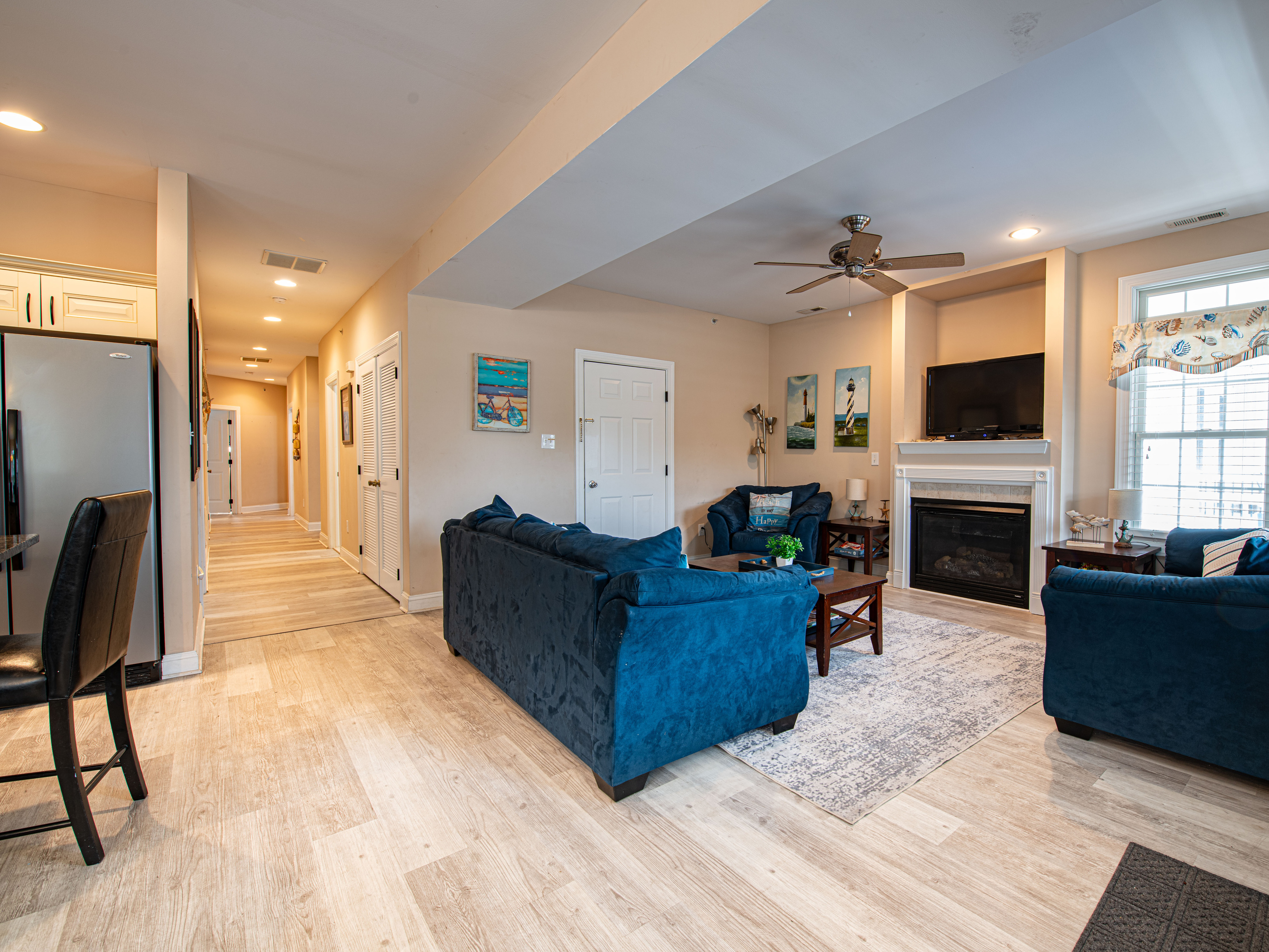 Living Room with Fireplace, Mounted TV, Blue Seating, and Hallway View