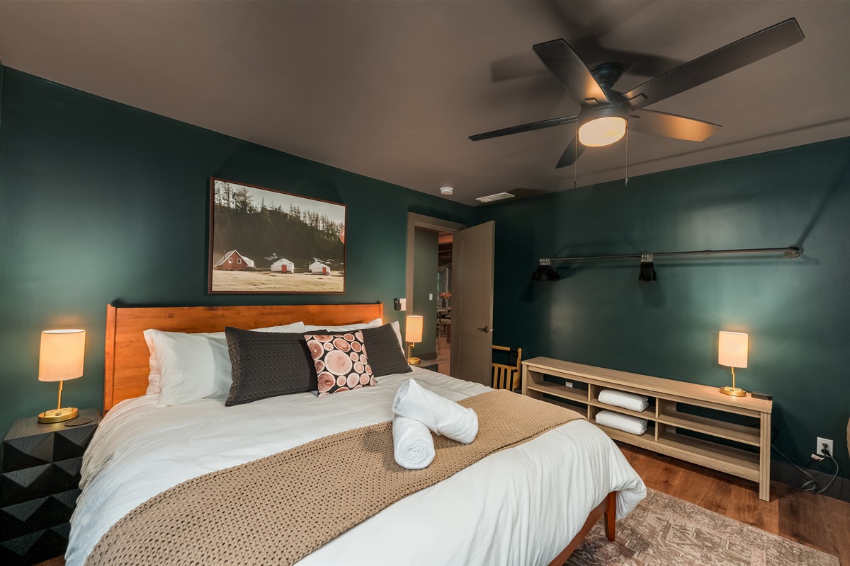 A modern king bedroom featuring rich moody tones, curated décor, and a spacious layout designed for total relaxation.