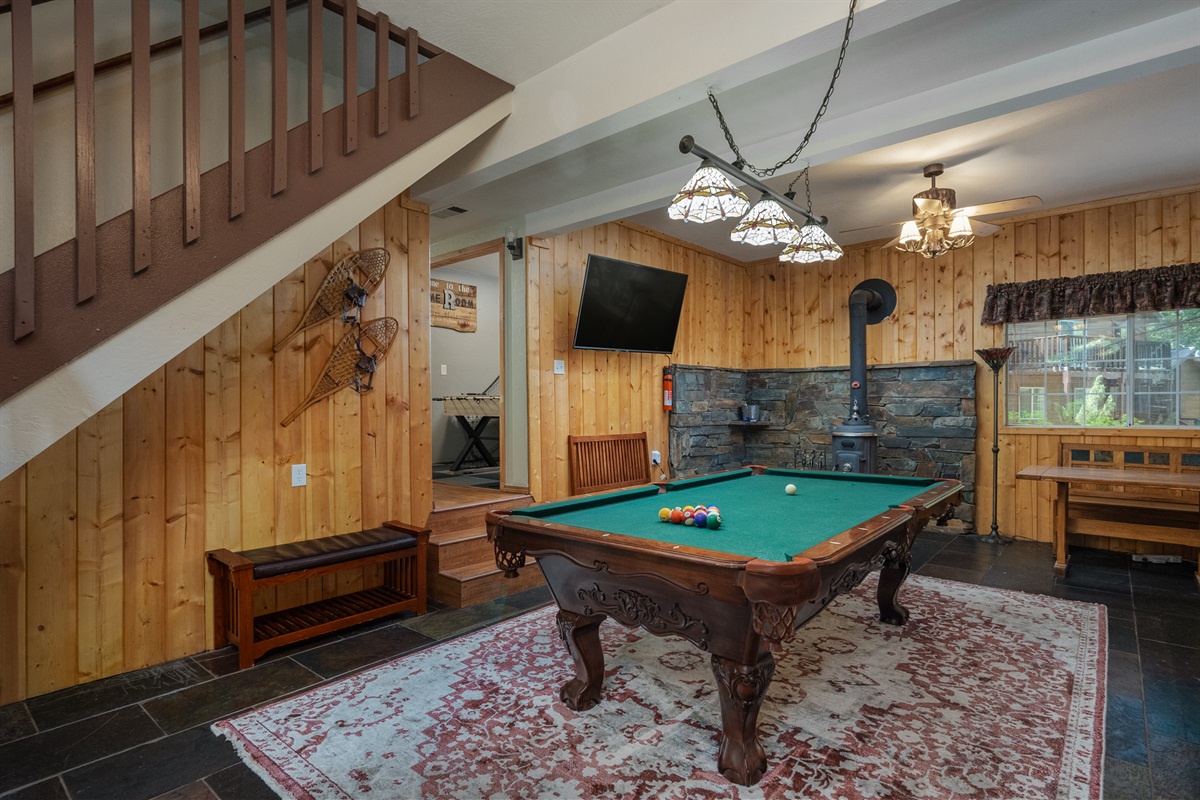 Step into the first room, featuring a pool table, a TV, and a wood-burning fireplace. Sofas and a table provide a cozy spot to unwind and entertain.