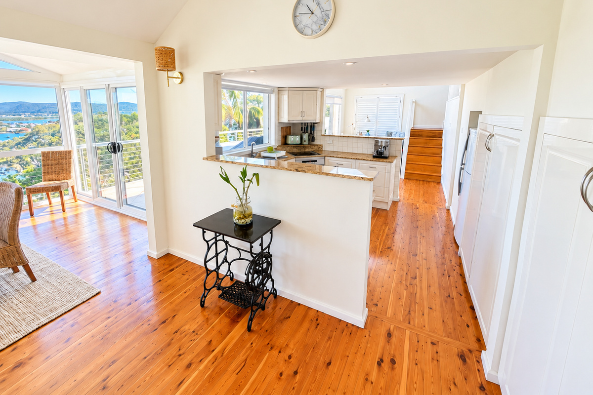 A bright and welcoming kitchen sits at the heart of the home, connecting effortlessly with the dining area and beautiful water views. Warm timber floors and abundant natural light create a relaxed coastal atmosphere.