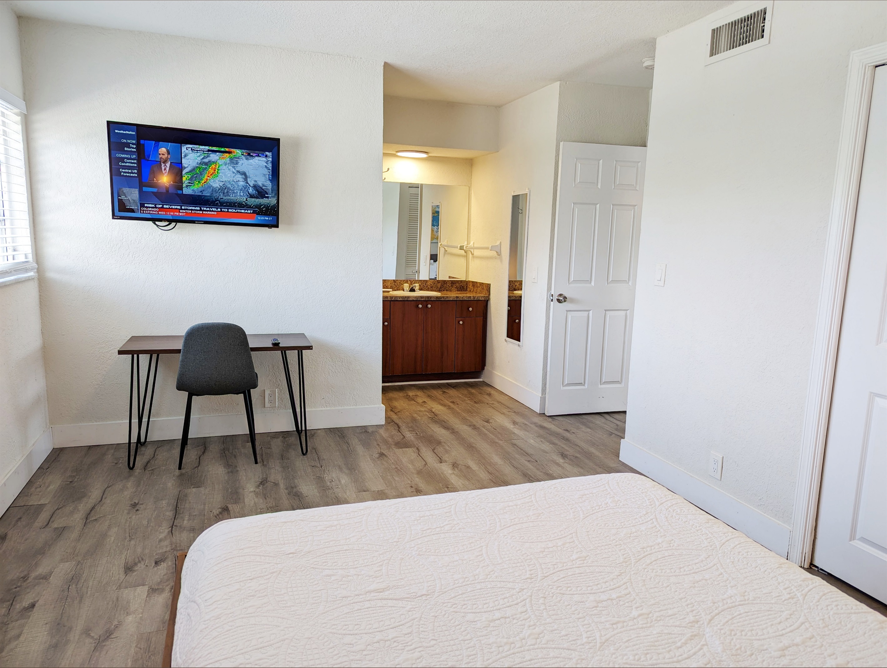 View in primary bedroom towards work station, smart TV and en suite bathroom.