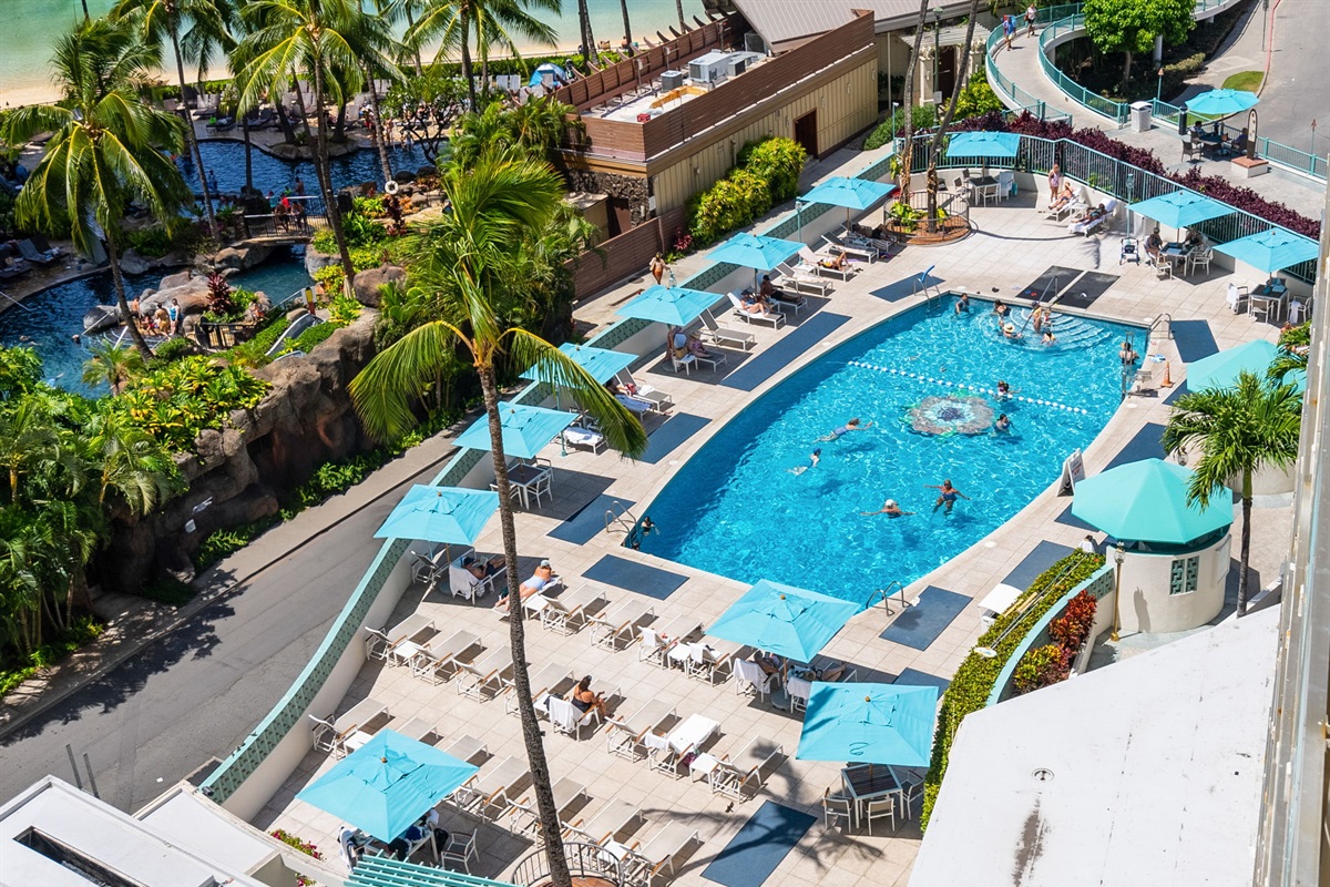 Ilikai Hotel pool deck with loungers and umbrellas for you to enjoy and relax.  Pool towels are provided on-site for guests