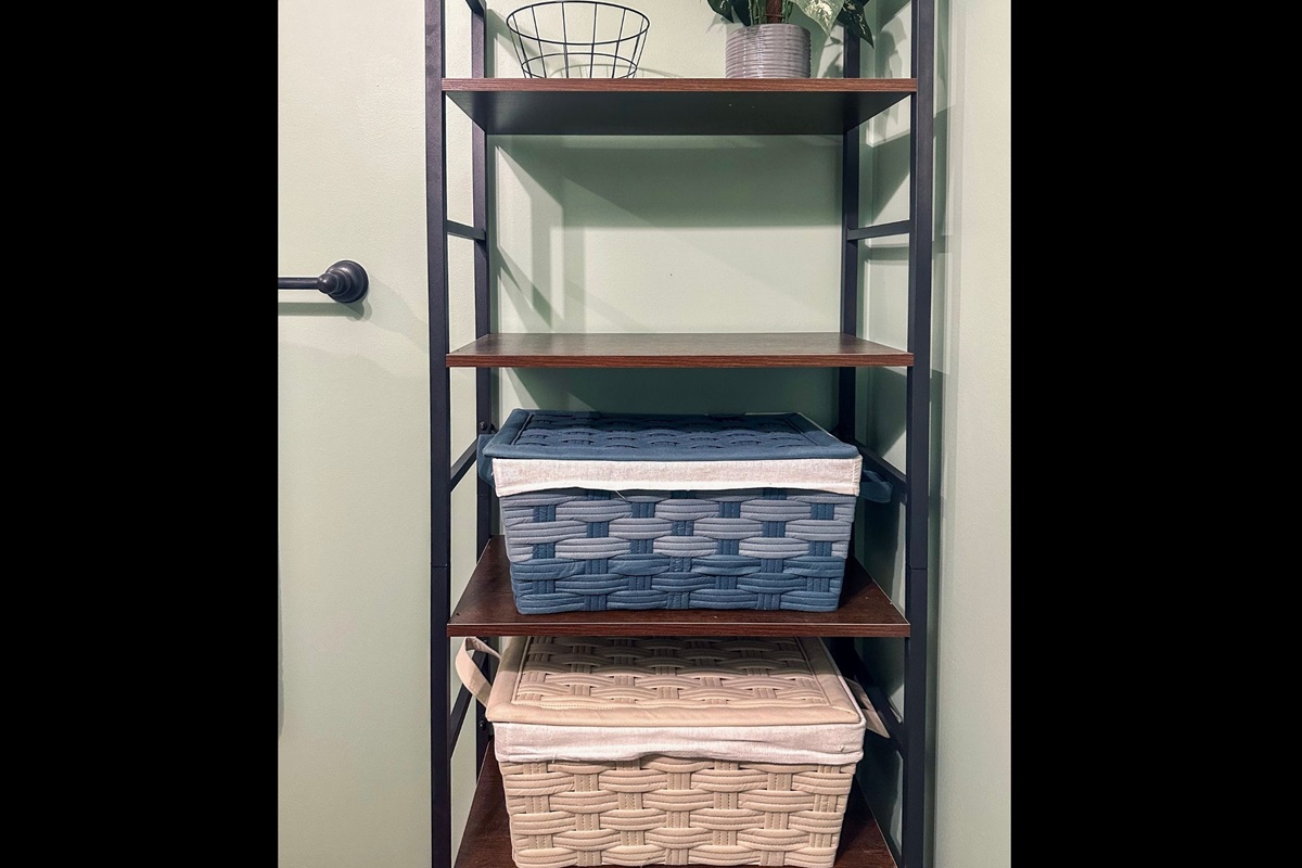Half bath shelving off the living room, neatly arranged with accessible storage for everyday essentials.