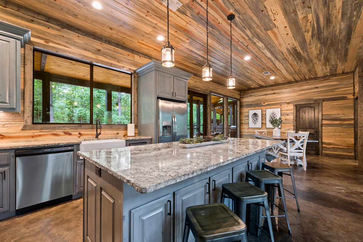 The kitchen boasts an expansive island with bar seating, complemented by pendant lighting and stainless steel appliances