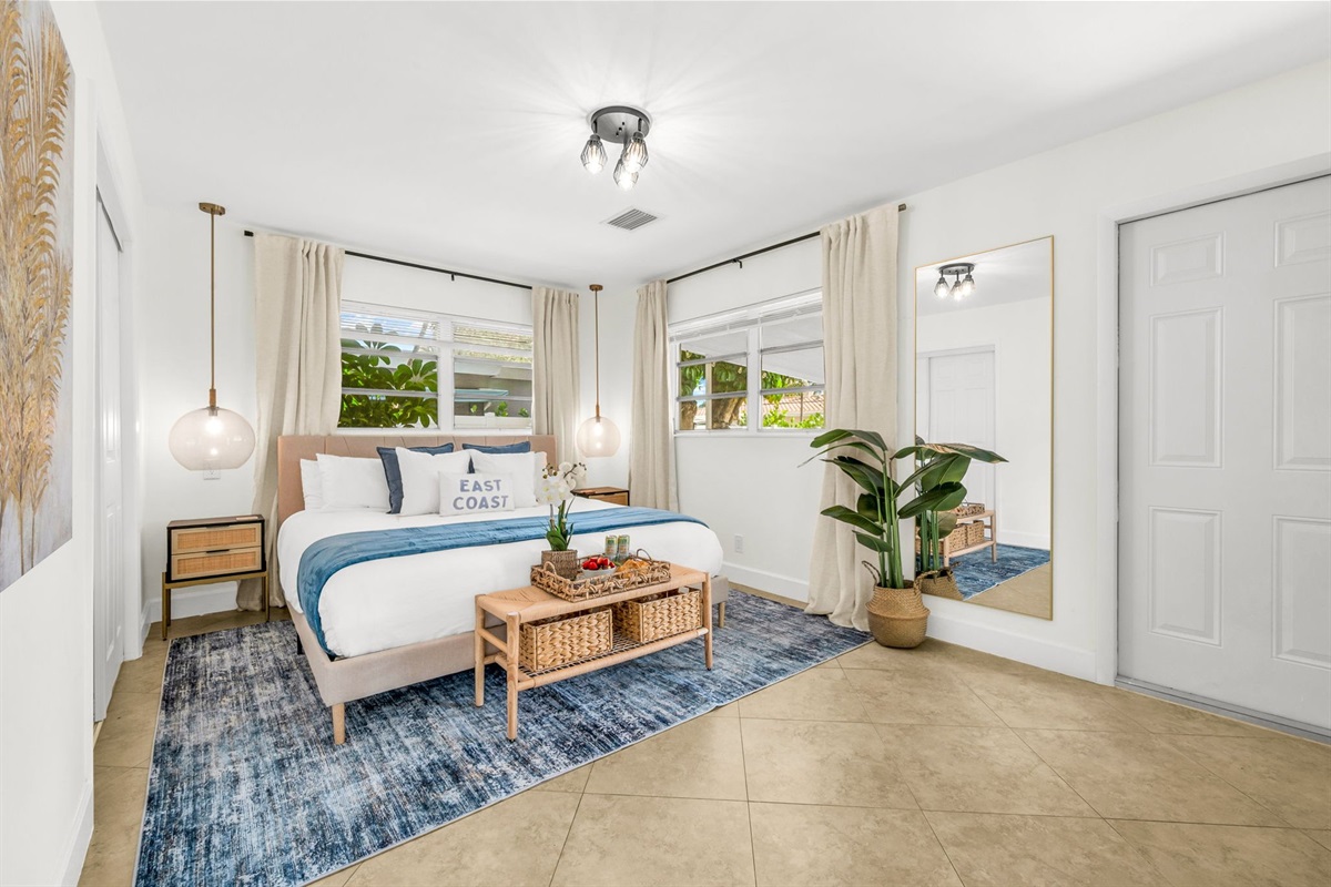 A bright and inviting primary suite featuring a hotel-quality king bed, dramatic pendant lighting, a sleek ensuite shower bath, and a Smart Fire streaming TV—your perfect private sanctuary.
