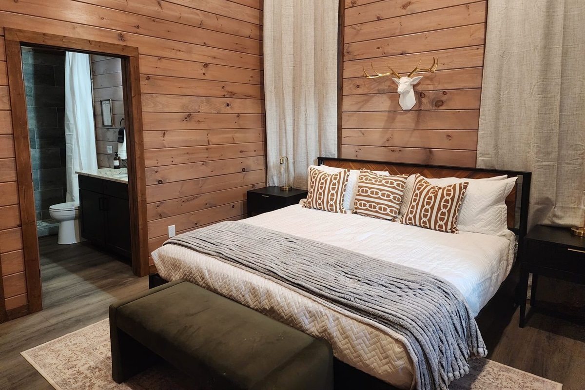 Queen bedroom with accent wall, reading lamps, and ensuite access.