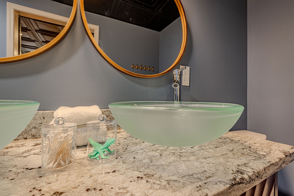 Experience a sleek and artistic retreat. This bathroom combines cool blue tones with frosted glass and gold accents for a tranquil, high-end feel.