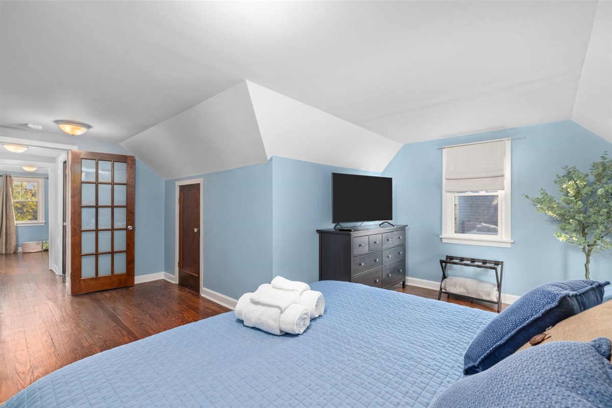 Upstairs bedroom 4 has plush king mattress, 50" flatscreen smart TV, night stands and bedside lamps, charging stations, dresser and closets for storage, and cozy space for baby. Pack-n-play with bassinet and retractable baby gate at top of stairs.