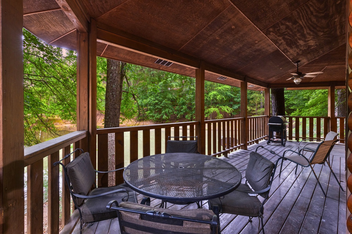 Covered deck with outdoor dining overlooking the pond.