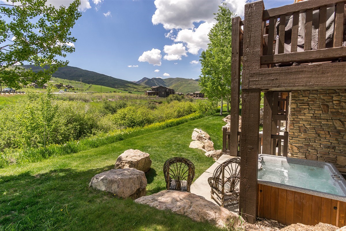 A tranquil outdoor space with hot tub and seating, surrounded by greenery and open skies—perfect for unwinding in nature.