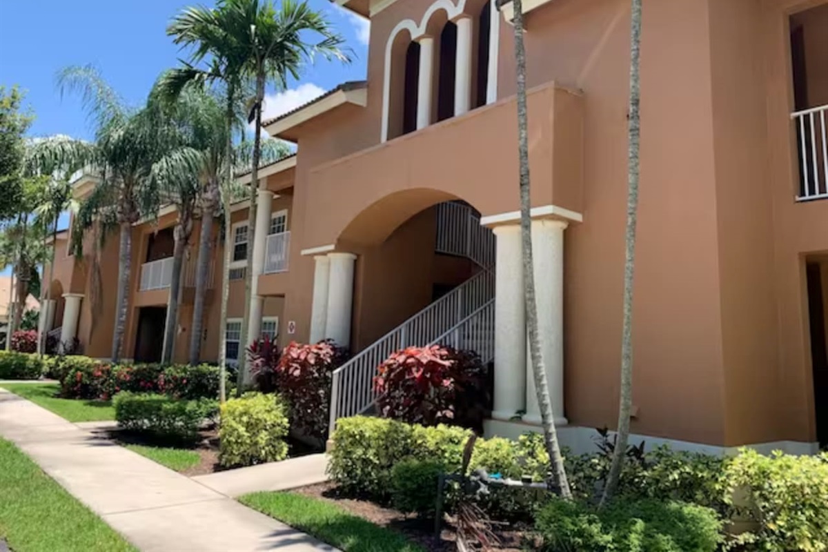 Exterior view of the building with tropical landscaping, covered walkways, and Florida-style architecture.