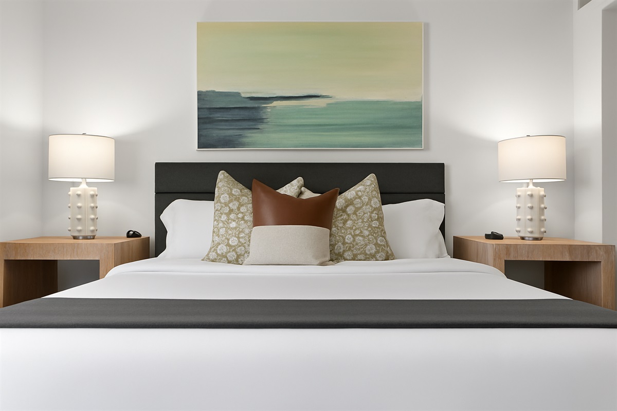 Elegant bedroom setup with dual nightstands, calming art, and a stylish wood-accented headboard.