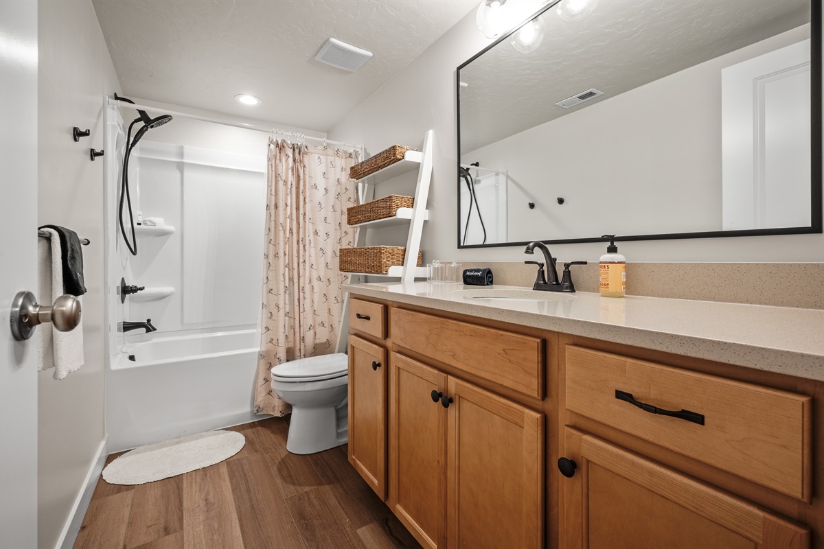 This well-appointed bathroom offers a sleek quartz countertop, ample counter space, a large mirror, and a full tub/shower combo.