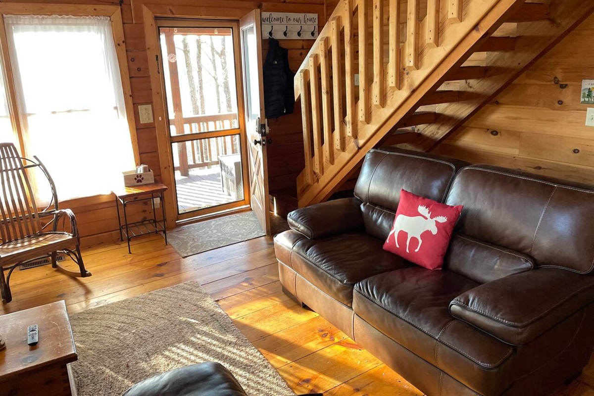 Leather couches in the living room with with large TV and nice view of mountains outside.