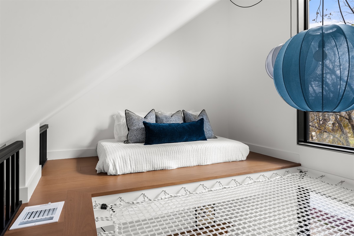 Cozy daybed tucked into the loft with large windows and peaceful treetop views—ideal for extra guests, reading, or afternoon lounging.