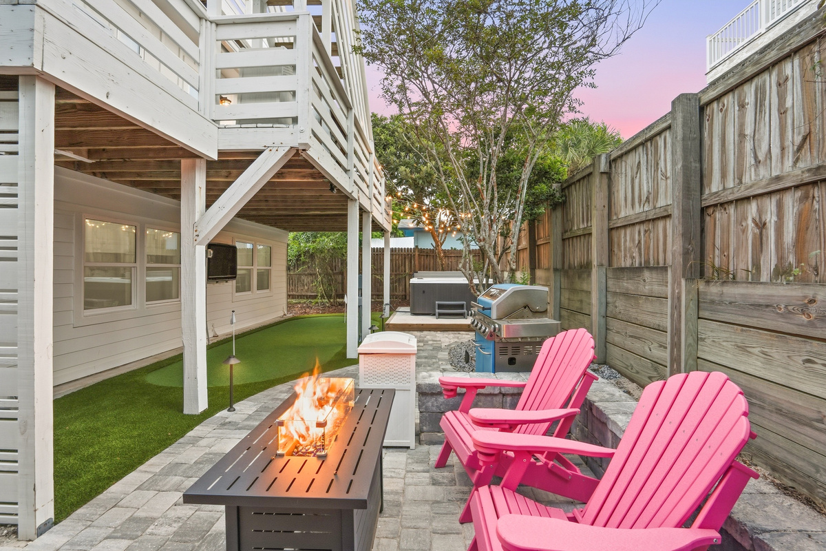 This photo features four sturdy pink outdoor chairs with built-in cup holders, arranged around a propane fire feature. We provide the propane, so you can just sit back, relax, and enjoy a cozy fire under the stars!