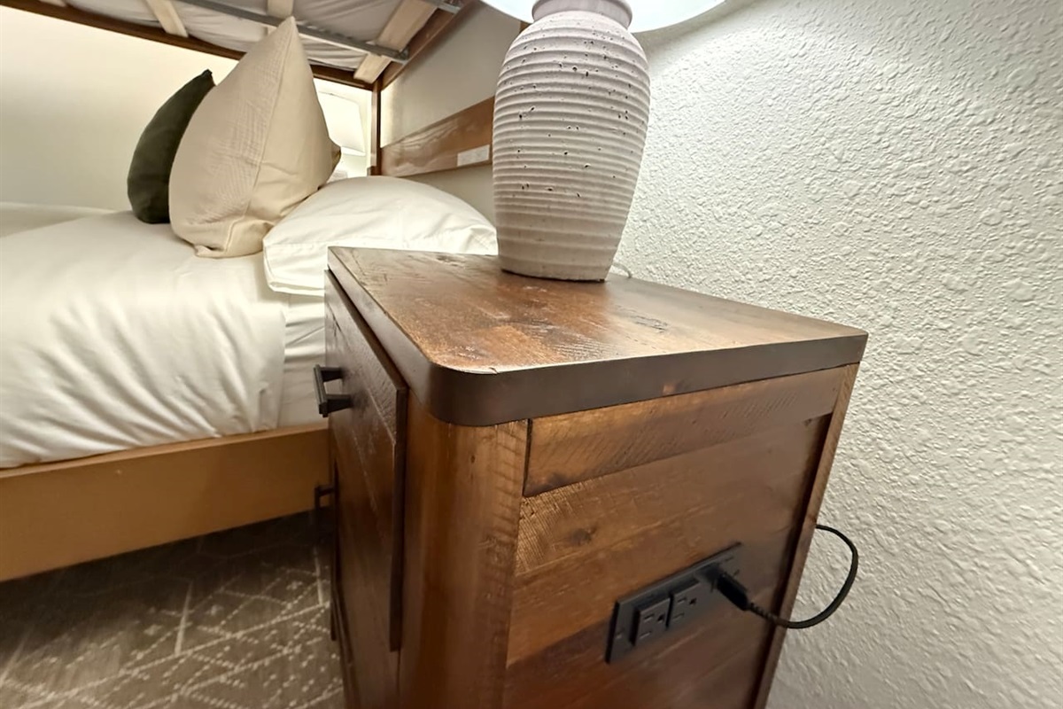 Nightstands with a lamp and electrical outlets and USB outlets on either side of the bed. 