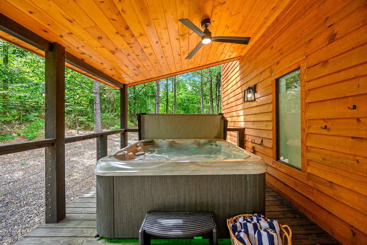 Private hot tub area with forest views and ceiling fan.