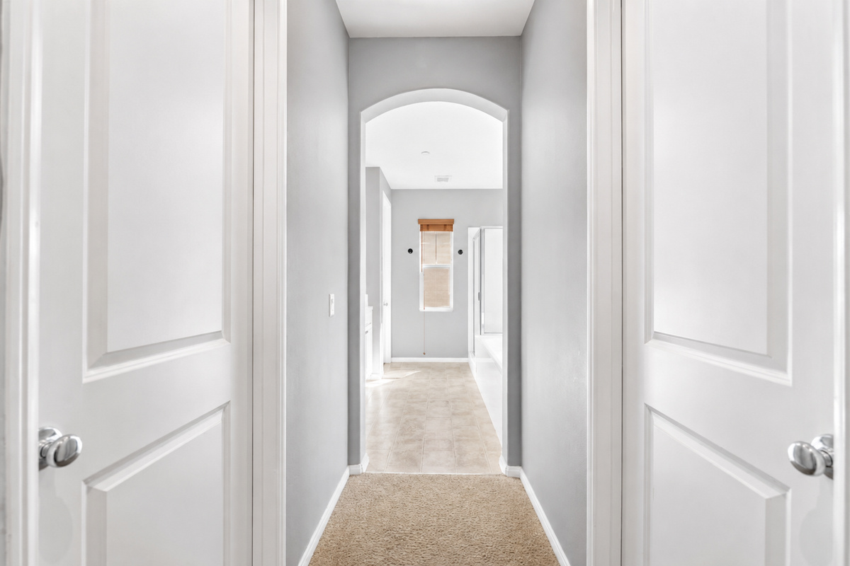 Hallway view with arched entry, soft carpet, and easy access between the bedrooms